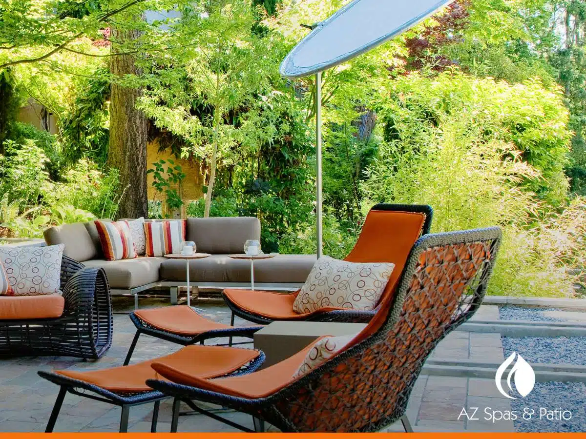 Modern patio furniture set in a lush garden, featuring lounge chairs and a sectional sofa